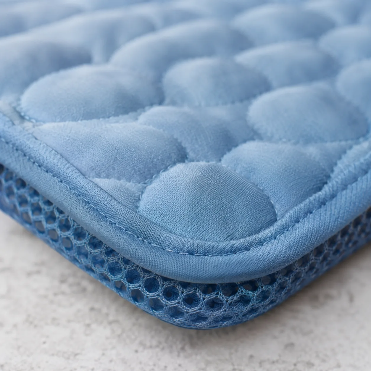 Macro shot of the edge of the Frimouf cooling mat: quilted surface on top and breathable mesh underneath